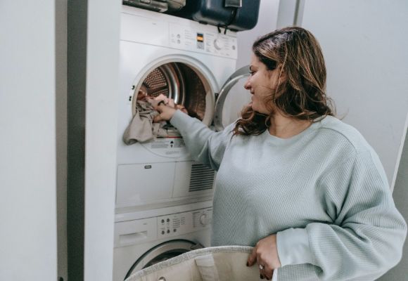 mulher colocando roupas para lavar em uma maquina